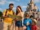 A real family of four at Disneyland Paris in summer, looking confused with a park map, a child in a rain poncho and sunglasses, and spilled popcorn near Sleeping Beauty Castle, showing classic theme park mistakes.
