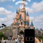Sleeping Beauty Castle with Wi-Fi symbol and smartphone, promoting the Disneyland Paris Wi-Fi and charging guide 2025