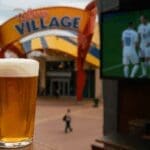 Feature image showing a pint of beer, Disney Village entrance and sports screen promoting the reopening of Sports Bar & Lounge at Disneyland Paris in 2025.