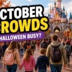 Disneyland Paris October crowds guide showing autumn park with Halloween decorations, pumpkins and moderate to busy crowds walking toward castle